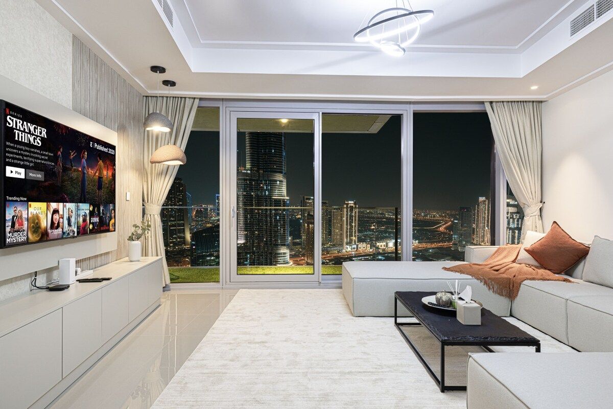 Una sala moderna con vista a la ciudad, un televisor de pantalla plana y un sofá.