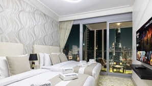 A modern hotel room with two beds, a large window with a city view, a flat-screen TV, and a SmartStay branded towel. - New 4BR Penthouse | Burj Khalifa View |Opera Grand (Dubai)