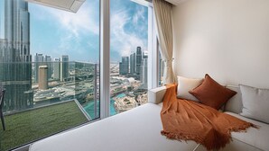A high-rise hotel room with a large bed, a view of a cityscape, and a balcony with a city view. - New 4BR Penthouse | Burj Khalifa View |Opera Grand (Dubai)