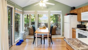 A kitchen with a dining area, wooden cabinets, a microwave, and a ceiling fan.