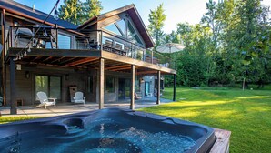 Una casa moderna con jacuzzi, mobiliario exterior y terraza cubierta.