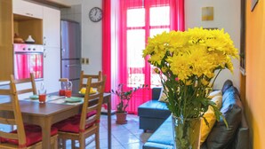 Un coin repas avec une table et des chaises en bois, un canapé et un vase rempli de fleurs jaunes.