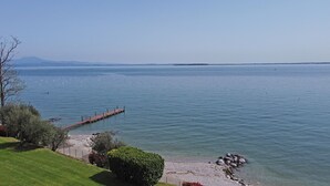 A lakeside view with a wooden pier extending into the water, surrounded by greenery and a clear sky. - Il Melagrano A6 by Wonderful Italy (Padenghe sul Garda)