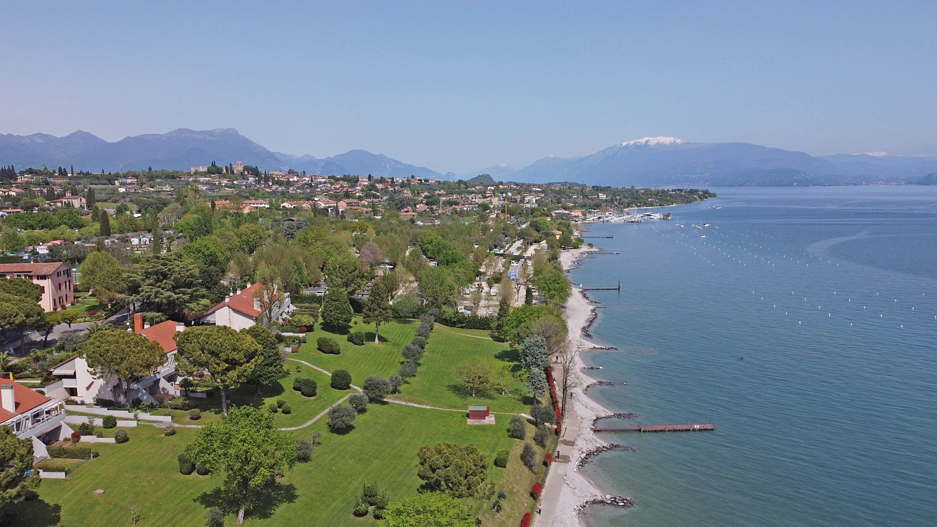 Une ville côtière dotée d’un port de plaisance, d’immeubles résidentiels et bordée par une chaîne de montagnes.