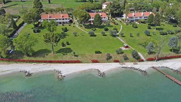 An aerial view of a residential area with multiple houses, a well-maintained lawn, and a body of water. - Il Melagrano A6 by Wonderful Italy (Padenghe sul Garda)