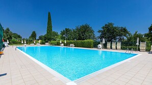A rectangular swimming pool with a tiled deck, surrounded by white umbrellas and lounge chairs. - Il Melagrano A6 by Wonderful Italy (Padenghe sul Garda)