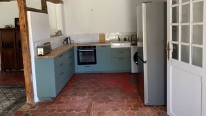 A kitchen with a stone tile floor, wooden beams, a built-in oven, a sink, and a refrigerator. - Charmantes Renoviertes Haus in Altem Anwesen mit Privatem Innenhof und Parkplatz (Moigny-sur-Ecole)