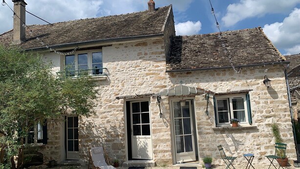 A stone building with a balcony, a door, and a window. There are two chairs and a potted plant outside. - Charmantes Renoviertes Haus in Altem Anwesen mit Privatem Innenhof und Parkplatz (Moigny-sur-Ecole)