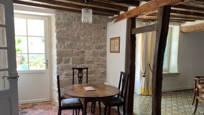 A dining area with a stone wall, wooden ceiling beams, a chandelier, and a tiled floor. - Charmantes Renoviertes Haus in Altem Anwesen mit Privatem Innenhof und Parkplatz (Moigny-sur-Ecole)