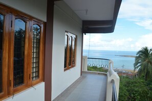 A balcony with a view of the sea, wooden windows, and a tiled floor. - Andaman Castle (Port Blair)
