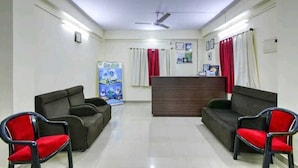 Un área de recepción con mostrador, dos sofás y dos sillones rojos.