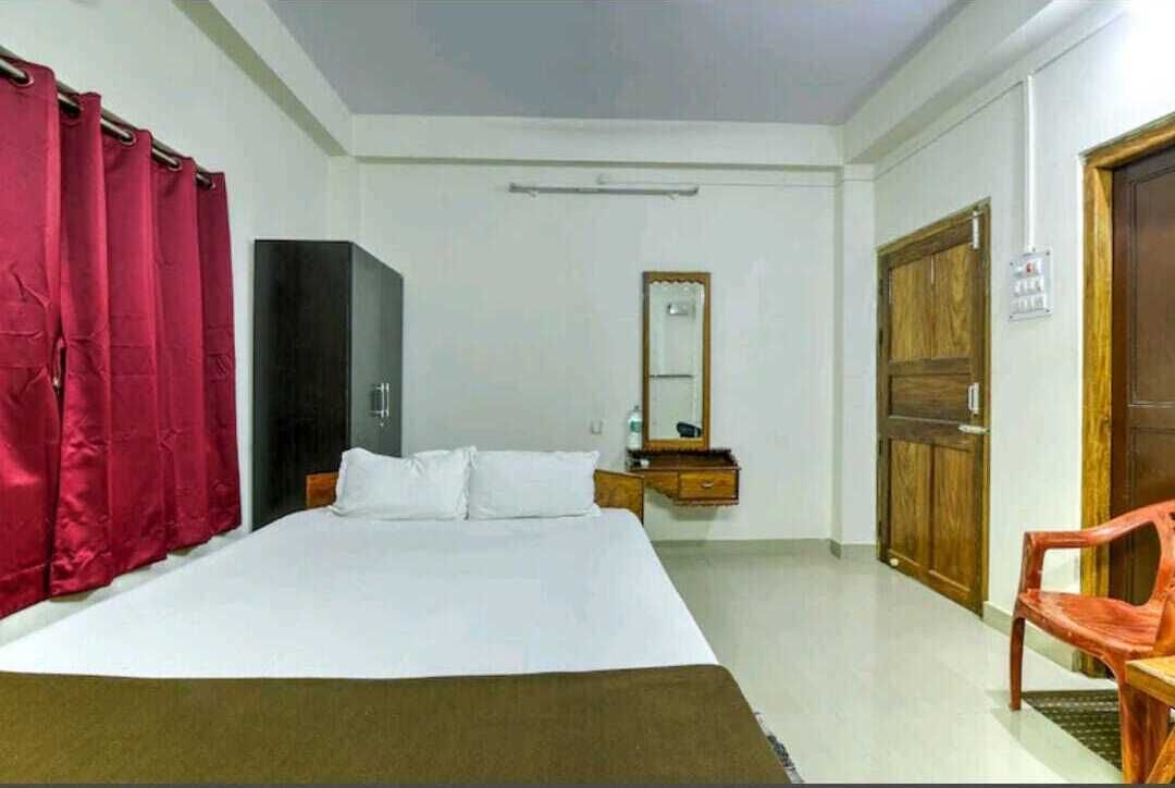 A bedroom with a bed, a wardrobe, a mirror, and a chair.