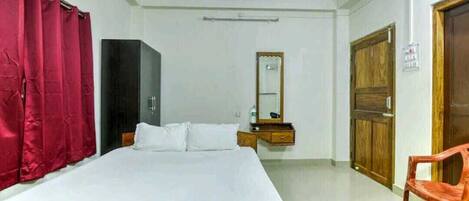A bedroom with a bed, a wardrobe, a mirror, and a chair.