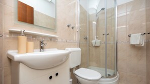 Een moderne badkamer met wastafel, toilet en douchecabine met glazen wanden.