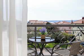 A balcony with a round table and wicker chairs, overlooking a residential area with houses and a distant view of the sea. - Double bed Room With Private Bathroom and Balcony (Kastela)