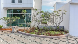 A modern building with a paved walkway and small plants. - Hotel O Alfa Residence (Cikarang)