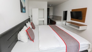 A modern hotel room with a neatly made bed, a flat-screen TV mounted on the wall, and a small kitchenette area. - Hotel O Alfa Residence (Cikarang)