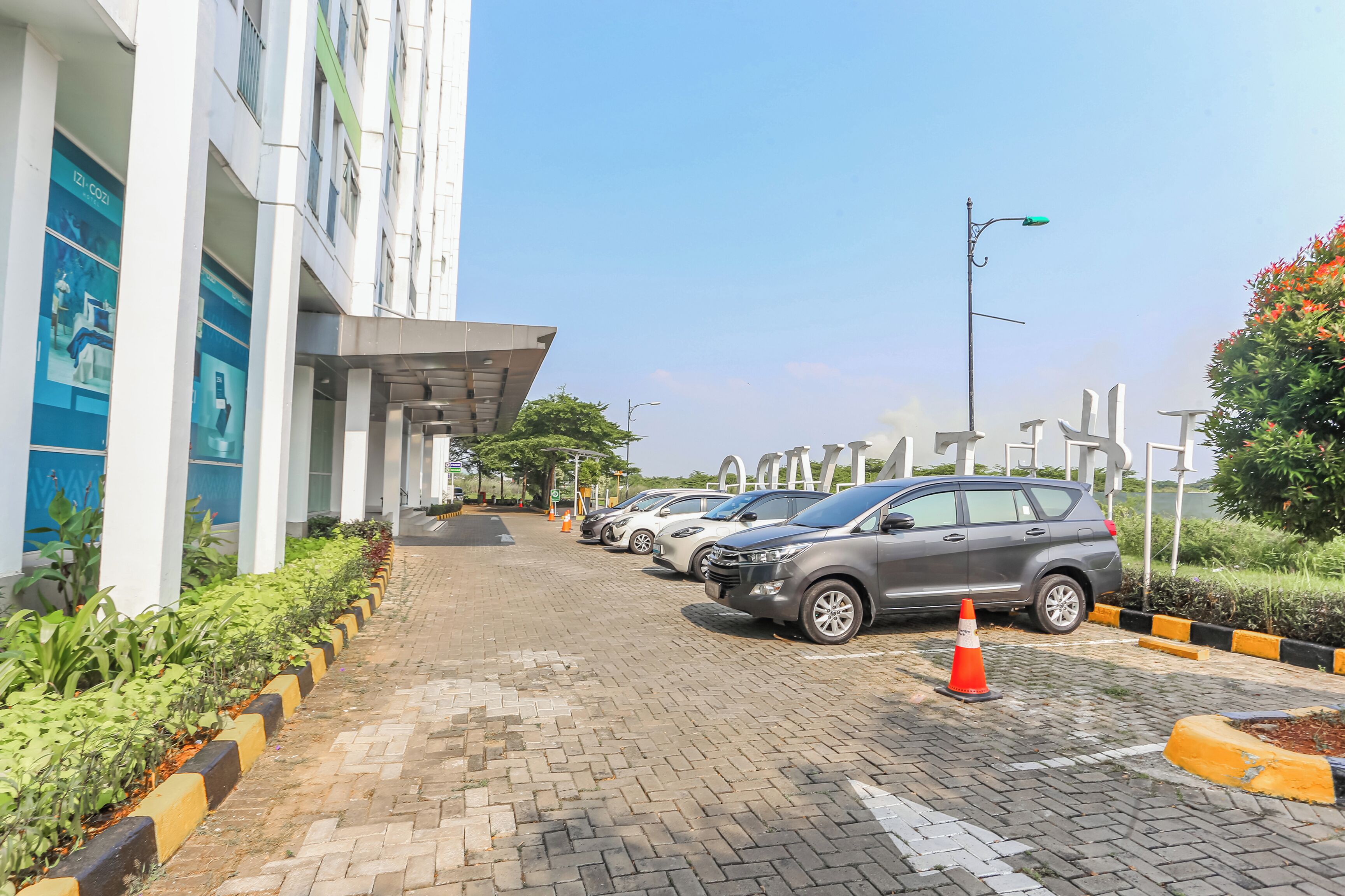 A parking area with cars, a building with columns, and a clear sky.