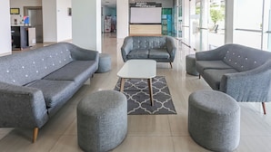 A modern lobby with grey sofas, ottomans, and a white coffee table. - Hotel O Alfa Residence (Cikarang)