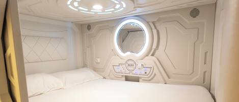 Una habitación con una cama, un espejo circular y un panel de control.