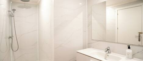 Une salle de bain moderne avec une douche, un lavabo et un miroir.