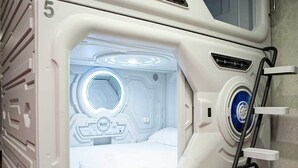 Una habitación con ventanal circular, cama y panel de control.