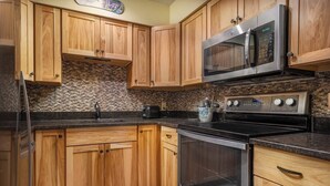 Eine Küche mit Holzausstattung, Mikrowelle, Backofen und einer Arbeitsplatte aus Granit.