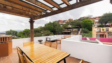 Una mesa y sillas de madera en una terraza con vistas a un pueblo en la ladera.