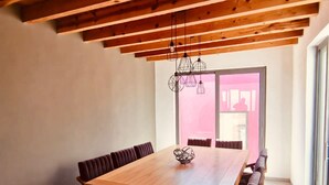 Comedor moderno con mesa de madera, bancos acolchados e iluminación colgante.