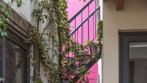Un callejón estrecho con un muro rosa, una reja de metal negro y un farol negro.