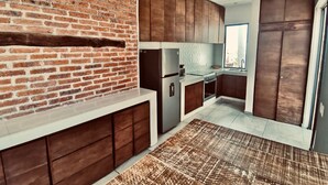 Una cocina moderna con pared de ladrillo, armarios de madera, electrodomésticos de acero inoxidable y un ventanal grande.