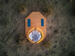 A hexagonal wooden structure with a central seating area and two blue vertical elements.