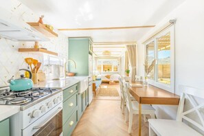 A compact kitchen with a stove, sink, and dining area with chairs and a table.