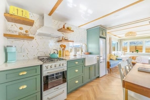 Una cocina moderna con estufa a gas, horno y comedor con mesa y sillas.