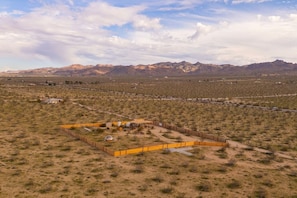 Zona aislada, cercada, con vegetación escasa y montañas a lo lejos.
