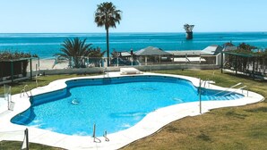 Une piscine à bord incurvé, entourée d’une pelouse et offrant une vue sur l’océan.