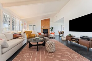 Smart-tv, eldstad, ett bordtennisbord och böcker