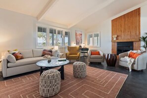 A living room with a sofa, armchairs, a coffee table, ottomans, and a fireplace. - Desert Heart | Stargazing Dome | Pool | Spa (Joshua Tree)