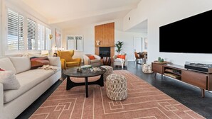 Una sala moderna con un sofá, sillones, una mesita de centro y un televisor.