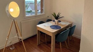 A dining area with a wooden table, blue chairs, a potted plant, and a floor lamp.