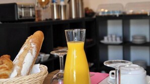 Ein Frühstückstisch mit Brot, Orangensaft in einem Glas und einer Kaffeekanne.