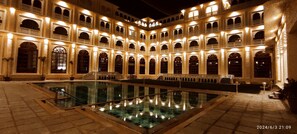 Un patio espacioso e iluminado con una piscina central y varios ventanales arqueados.