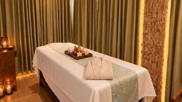 Una habitación bien iluminada con una cama, cabecera de madera, una mesita con velas y una alfombra tejida.