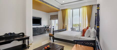 A hotel room with a bed, a sofa, a coffee table, a TV, and a balcony with a view.