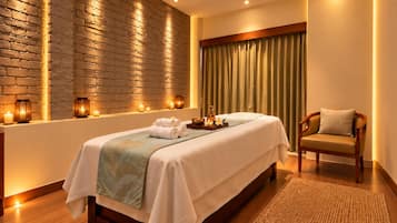 Ein Spa-Raum mit Massageliege, Kerzen und einem Holzstuhl.