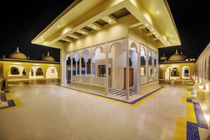 A well-lit, open-air lobby with a checkered floor pattern, featuring a central seating area and a covered entrance with arches. - Sterling Aravalli Udaipur (Udaipur)