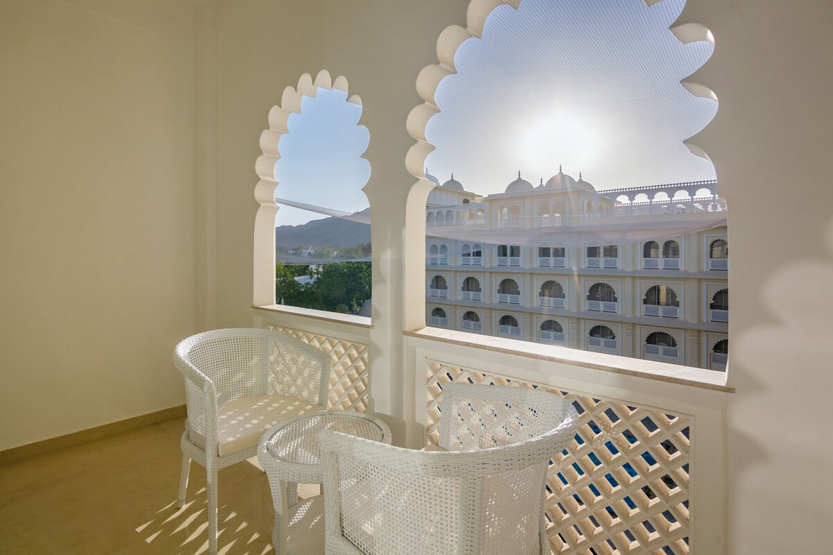A balcony with white wicker furniture and a view of a traditional building with arches and domes.