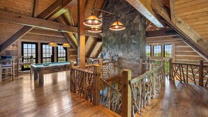 A spacious room with wooden beams, a pool table, and a stone wall. - Mountainside 5-BR Ski-In/Out Okemo Villa (Ludlow)