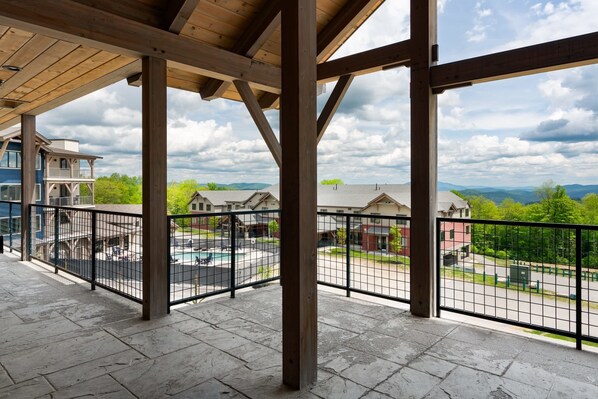 A covered outdoor area with a view of a residential neighborhood, including houses and a swimming pool. - Ski-In/Out Condo on Okemo Mountain (Windsor County)