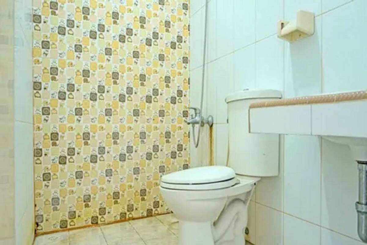 Un baño con inodoro, ducha y pared revestida de azulejos con diseño geométrico.